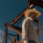landman-billy-bob-thornton-tommy-norris-talking-on-his-phone-while-standing-outside-oil-rig-equipment.jpg