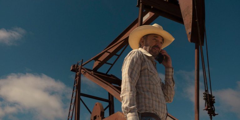 landman-billy-bob-thornton-tommy-norris-talking-on-his-phone-while-standing-outside-oil-rig-equipment.jpg